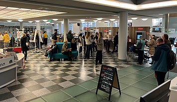 Fachtag Lesepat:innen und Lehrkräfte 2025 Im Foyer der Stadtbibliothek Karlsruhe treffen TeilnehmerInnen zum Fachtag für Lesepat:innen und Lehrkräfte ein. Es sind Personen im Gespräch zu sehen.