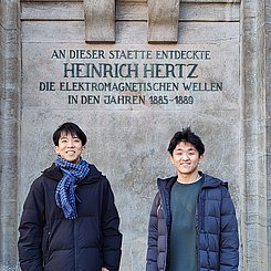 Die beiden Austauschstudierenden unter einer Büste von Heinrich Hertz.