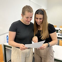 Zwei Studierende schauen sich ein Handout an.